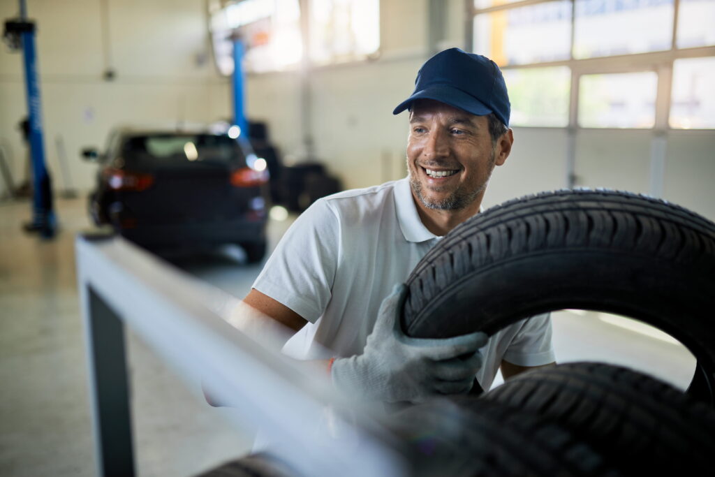happy mechanic working with tires car service workshop (1)