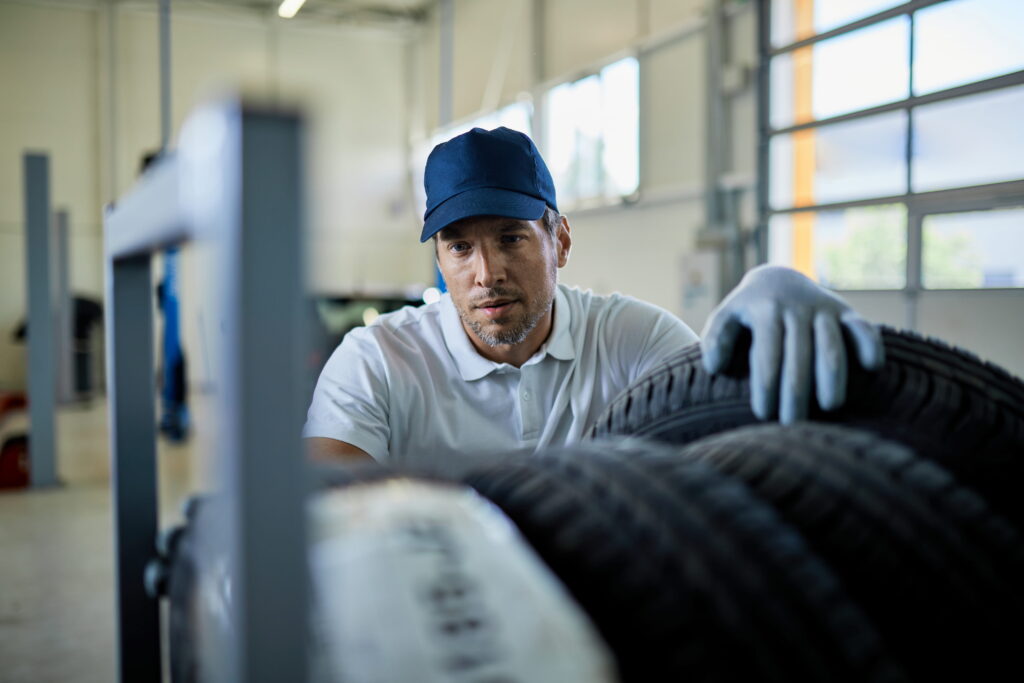 mid adult mechanic working with car tires auto service workshop (1)